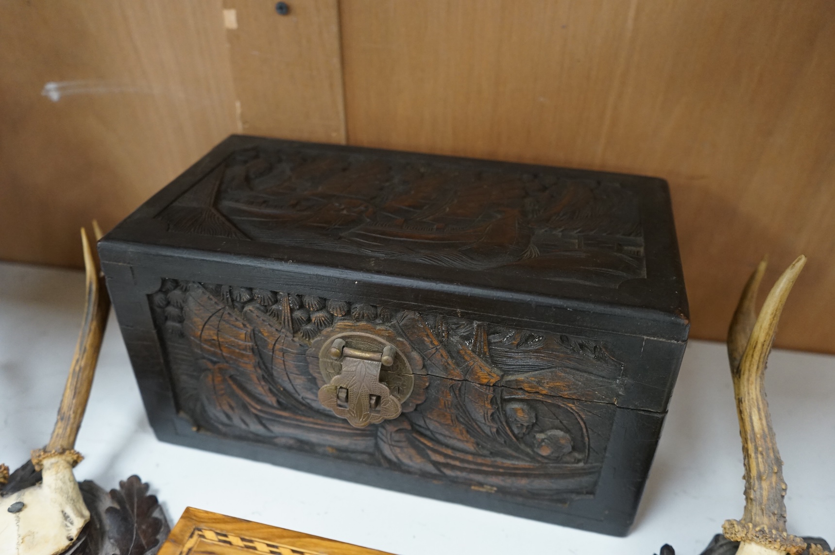 A Chinese carved wood box, two pairs of mounted deer horns, two carved wood cherub heads, an ashtray and an olivewood box, large box 29.5cm x 15cm high. (7)